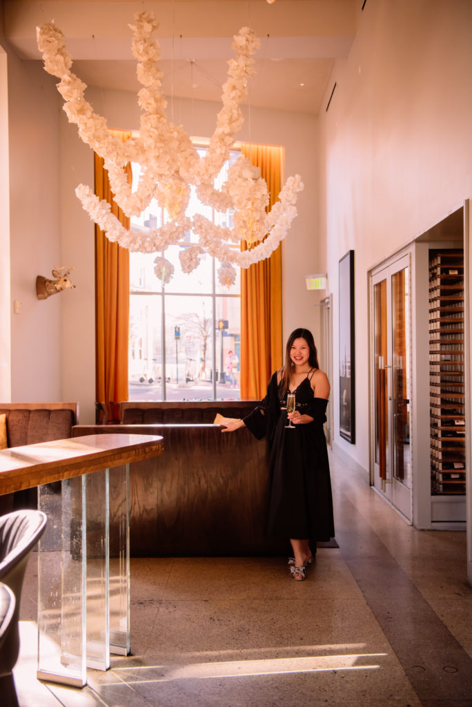 Woman holding champagne glass in Counting House, the restaurant inside of 21c Hotel in Durham