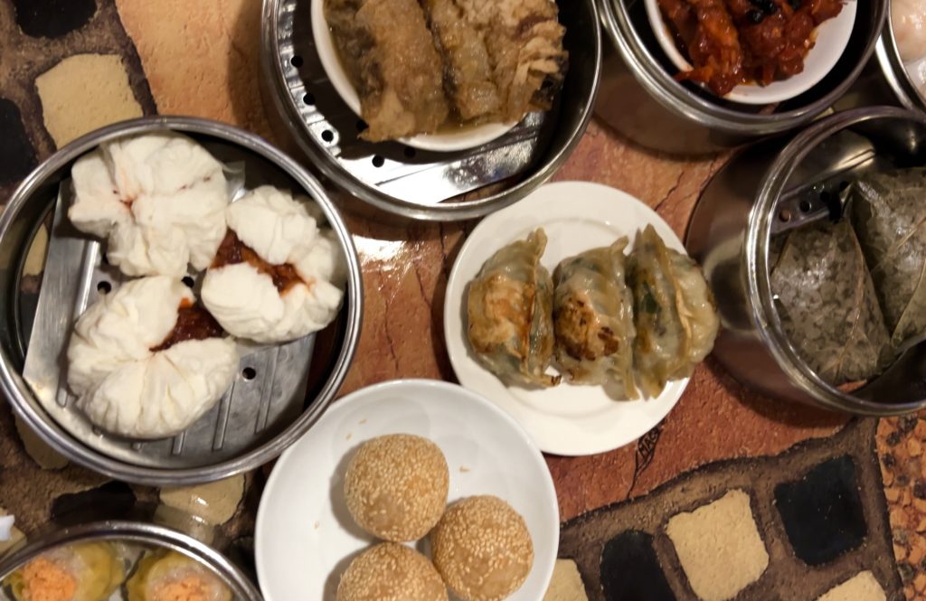 Overhead photo of Dim Sum dishes. Pictured: steamed baos with Chinese barbecue, dumplings, sticky rice. All from restaurant serving Push-Cart Dim Sum in  North Carolina